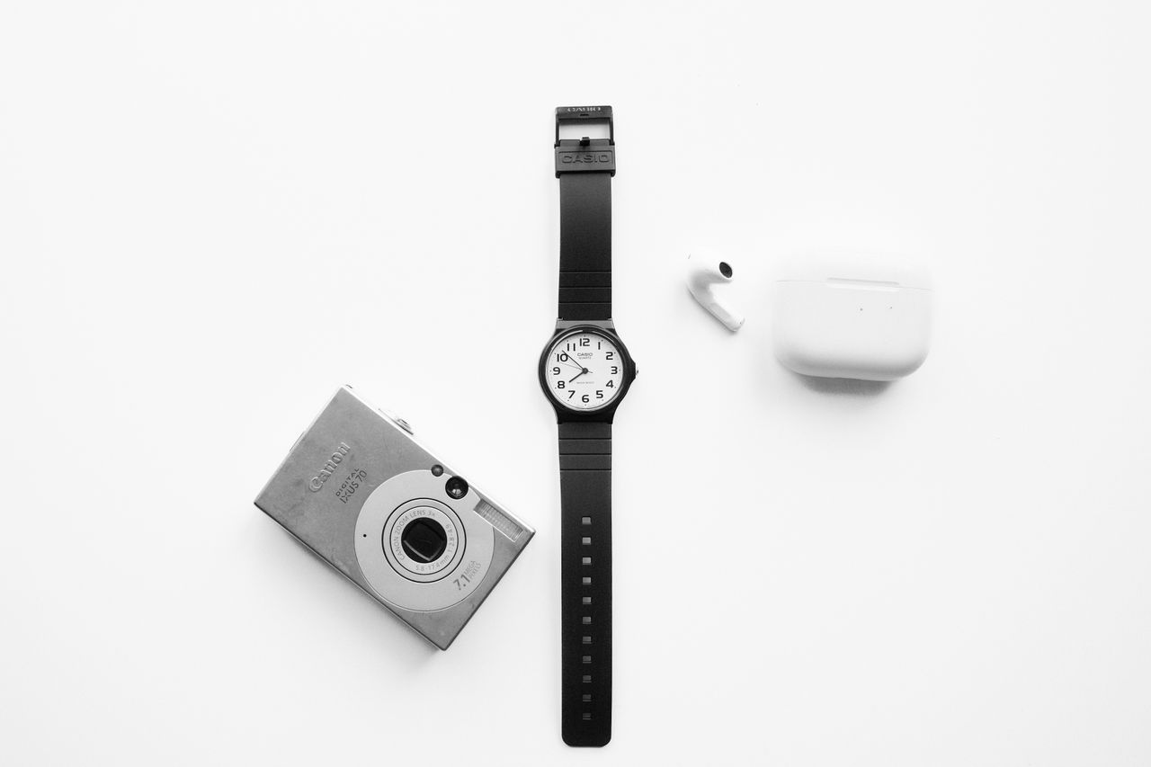black watch camera and earbuds arranged on a white background for a mo