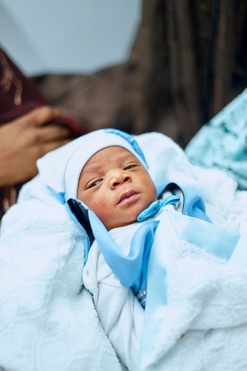 Free Cute newborn baby wrapped in a blue blanket, looking peacefully at the camera. Stock Photo