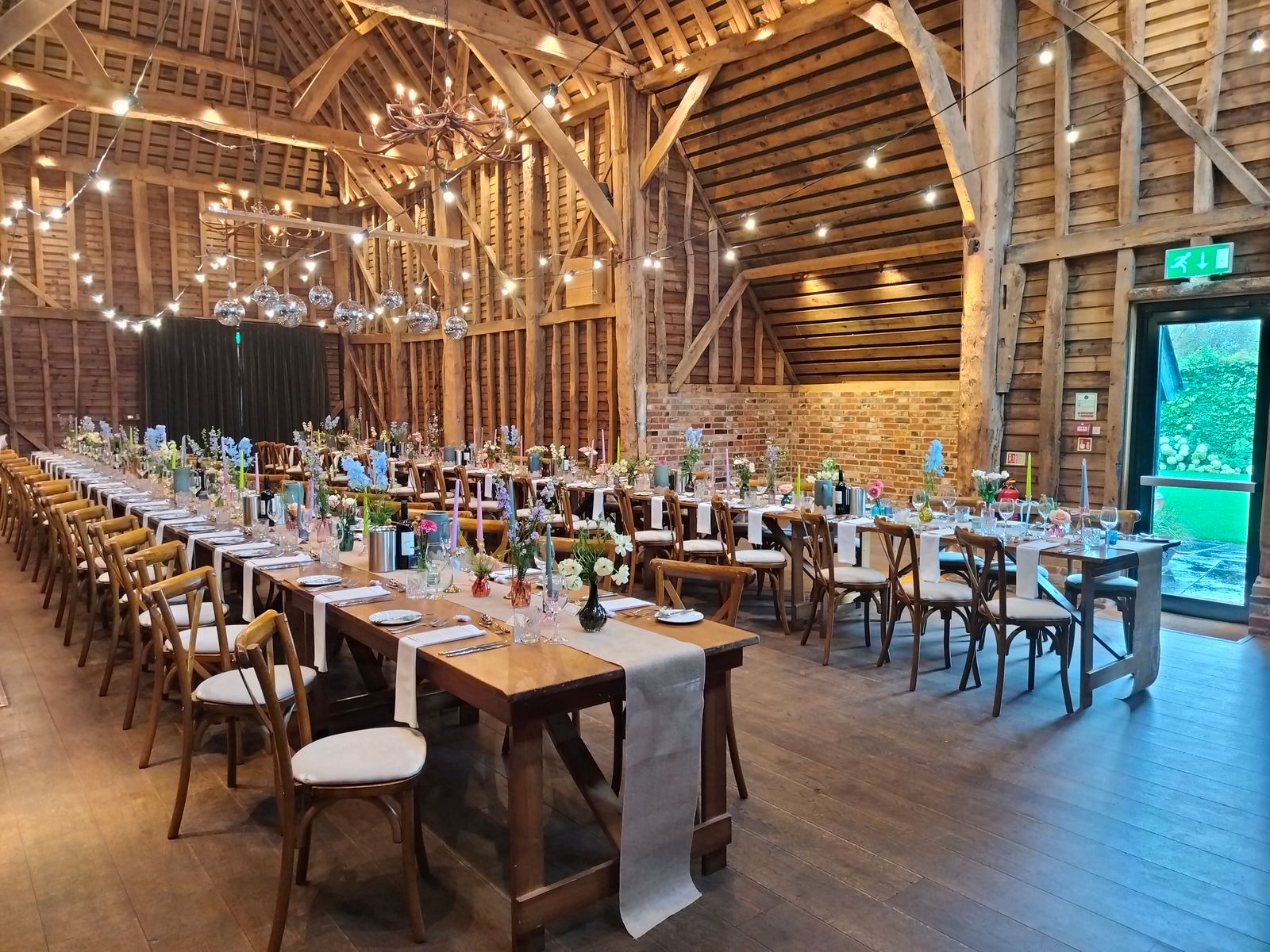 Beautifully decorated rustic barn set for a wedding reception with tables, chairs, and floral arrangements.