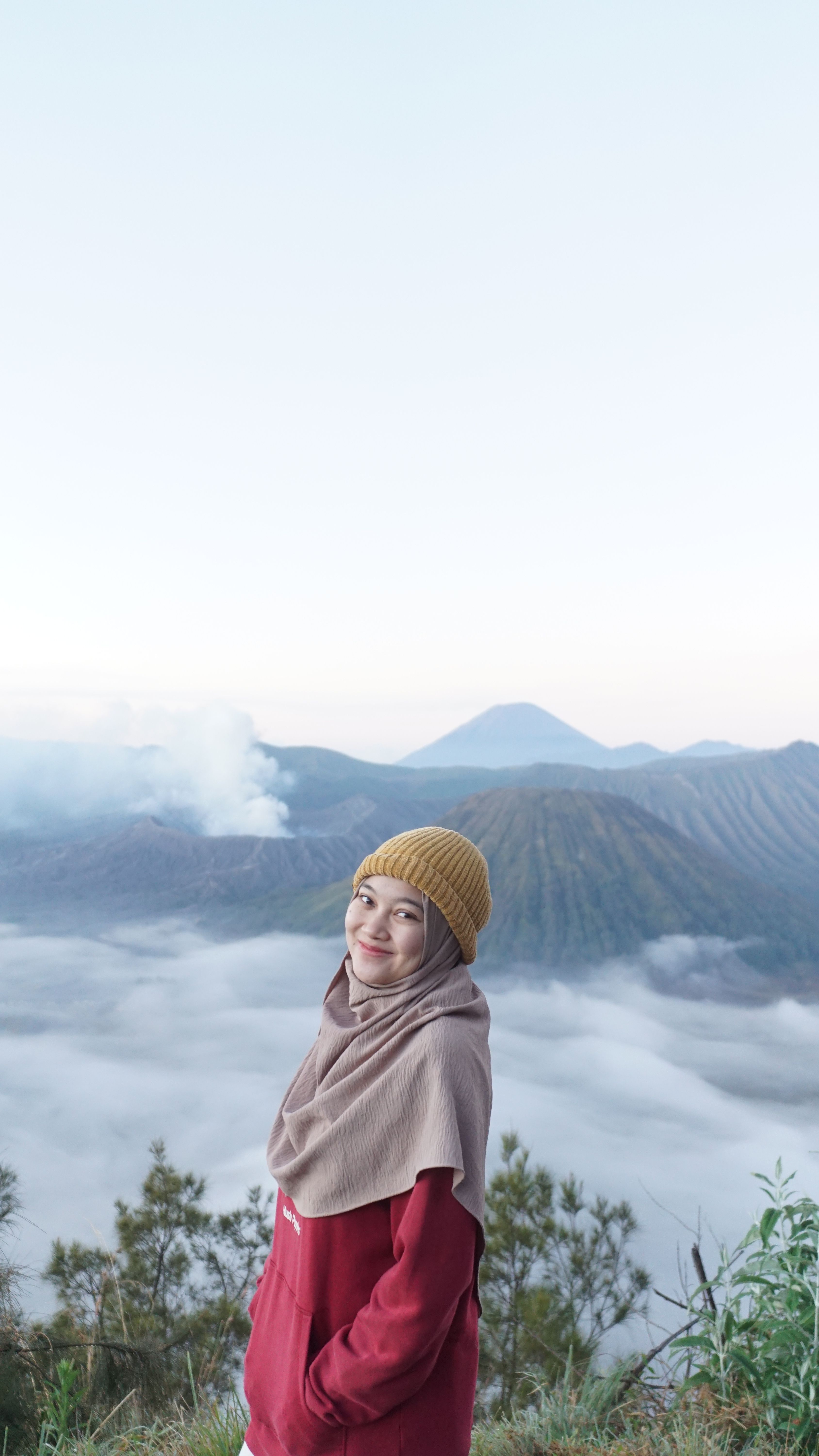 A woman in a hijab enjoys the scenic Mount Bromo landscape at sunrise in East Java, Indonesia.