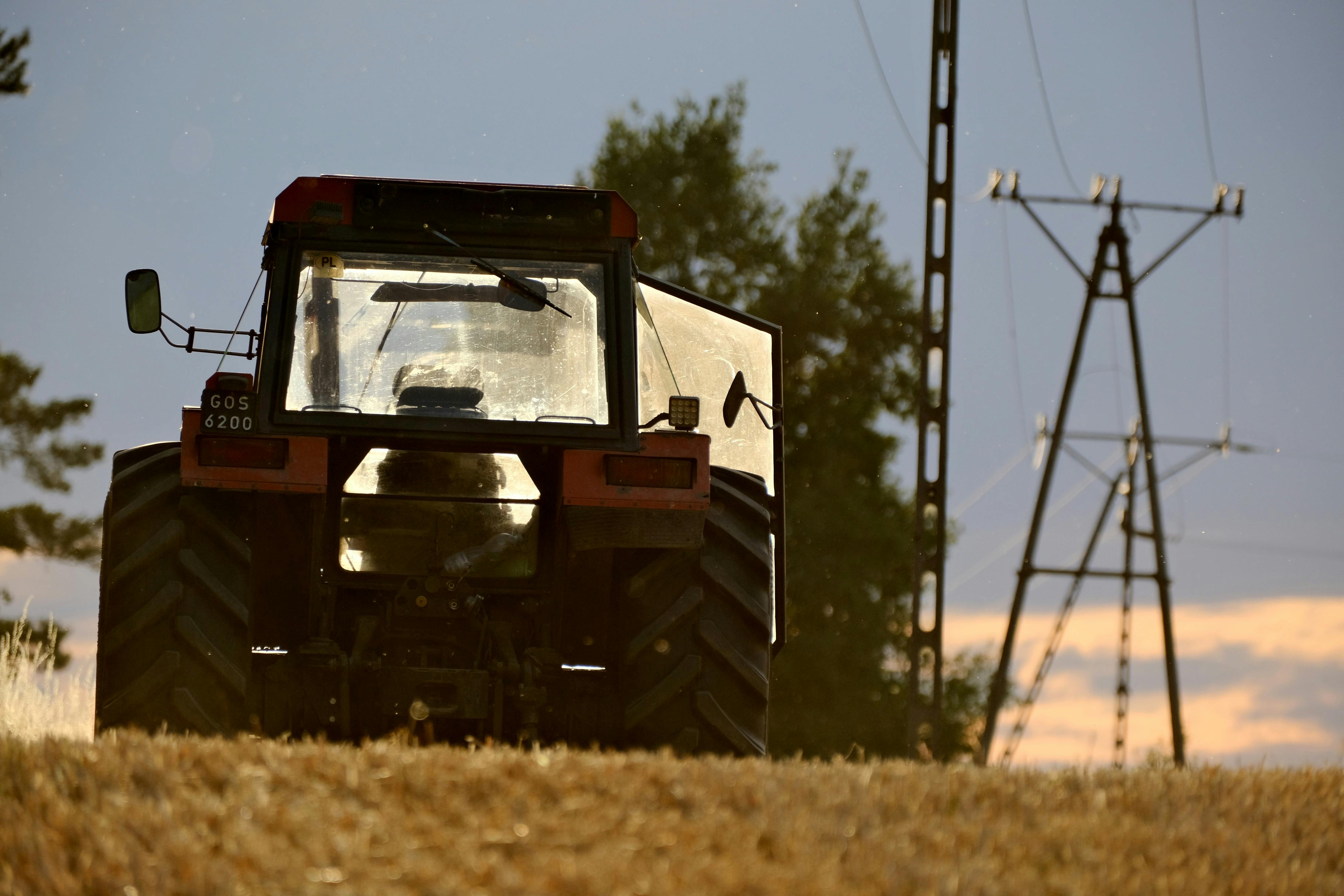 Wheat field with a tractor against an agricultural landscape at sunset