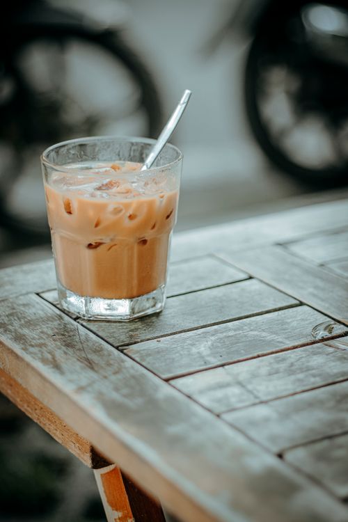 Free Glass of iced coffee with a straw on a rustic wooden table, outdoors. Stock Photo