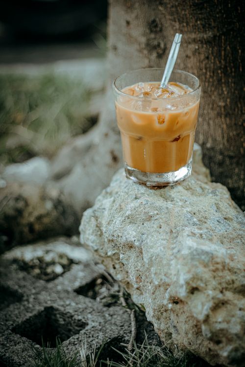 Free A refreshing glass of iced coffee with a straw outdoors on a stone surface. Stock Photo