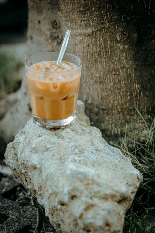 Free A refreshing iced coffee in a glass sits on a rock outdoors in summer. Stock Photo