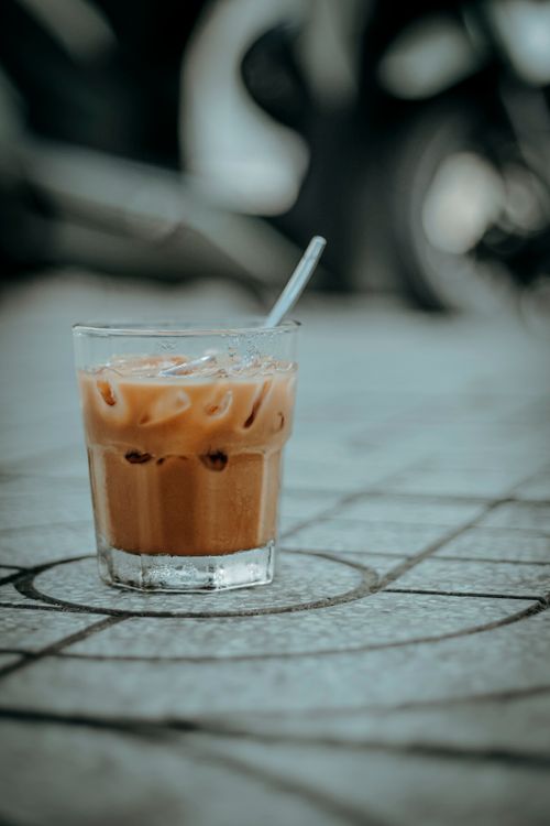 Free Close-up of iced coffee with straw on urban pavement, outdoor city setting. Stock Photo