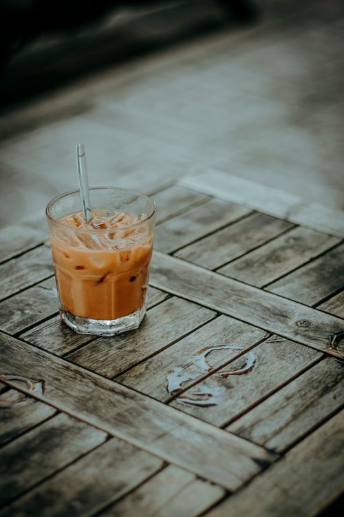 Free A glass of iced coffee on a rustic wooden table outdoors, perfect for summer refreshment. Stock Photo