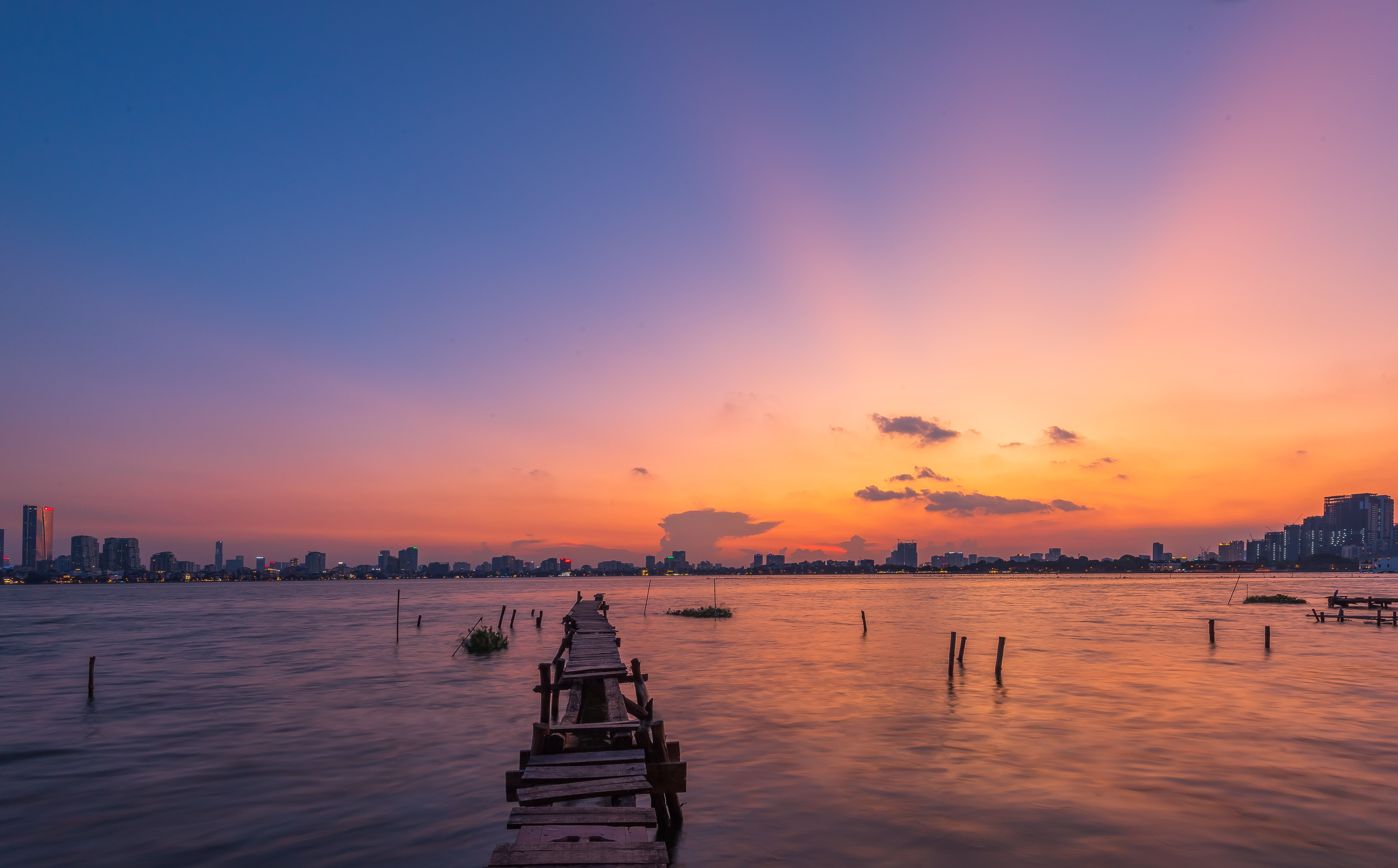 Serene Sunset Over City Skyline and Pier · Free Stock Photo