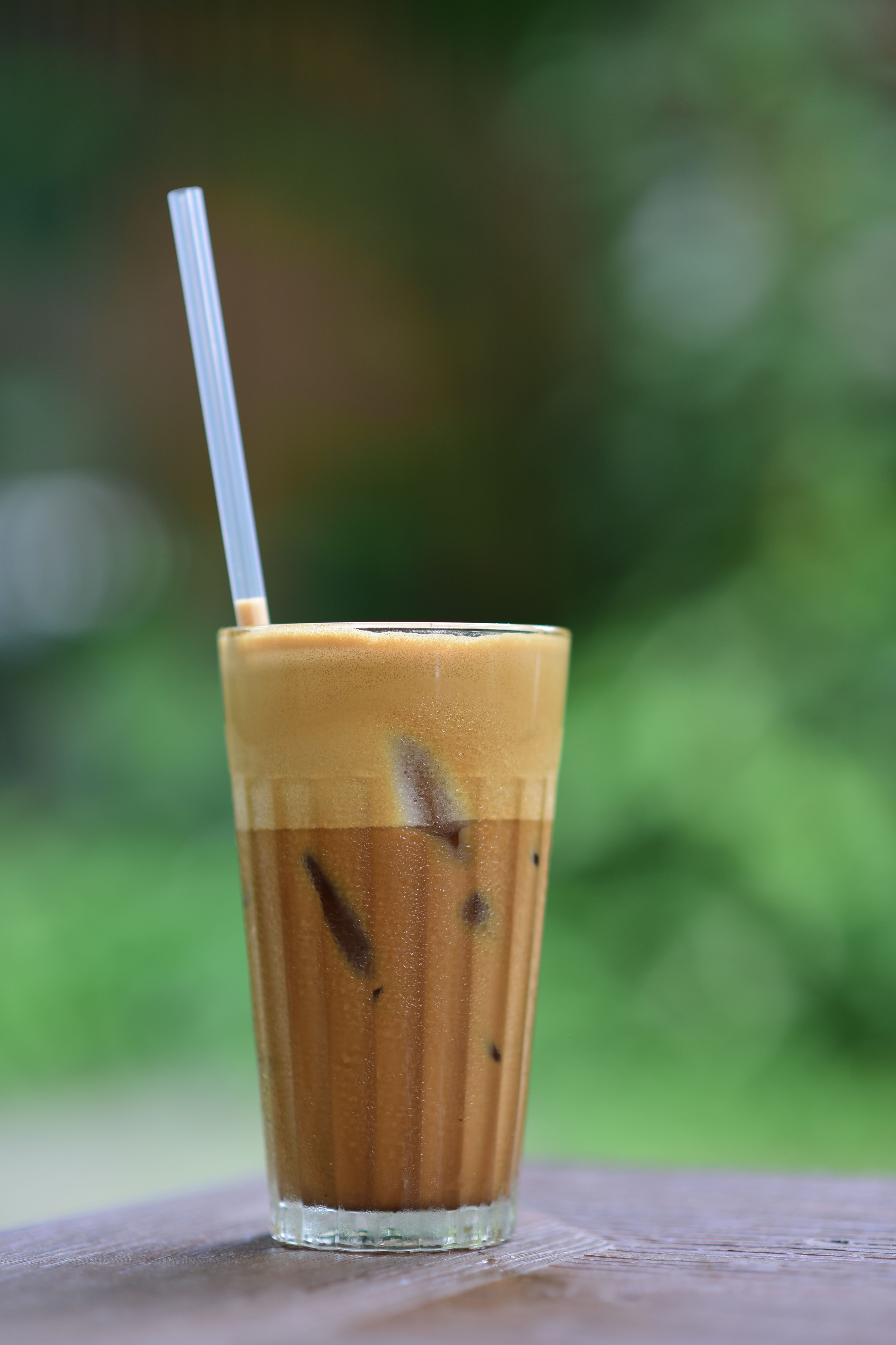 A glass of iced coffee topped with a thick layer of white cold foam that holds its shape before being stirred in