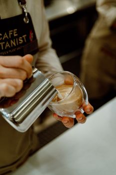 A barista expertly pours coffee with milk in a glass at a Baku coffeeshop. Perfect for coffee enthusiasts.
