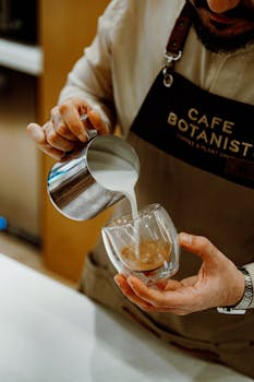 Barista expertly pouring milk into coffee at Cafe Botanist in Baku, Azerbaijan.