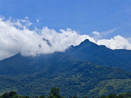 Free A scenic view of a lush green mountain topped with dramatic cloud formations. Stock Photo
