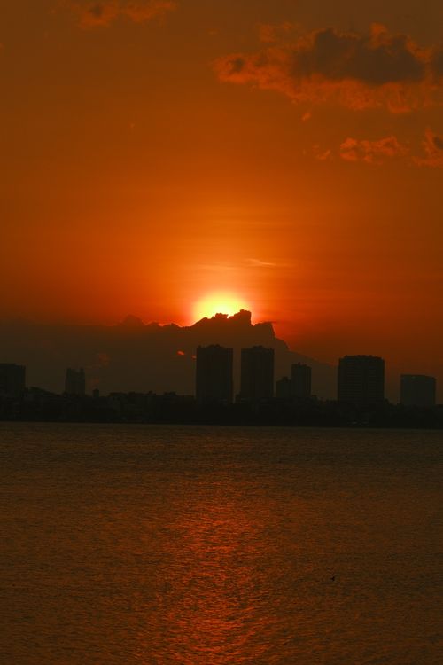 Free Beautiful orange sky and city silhouette at sunset over calm waters. Stock Photo