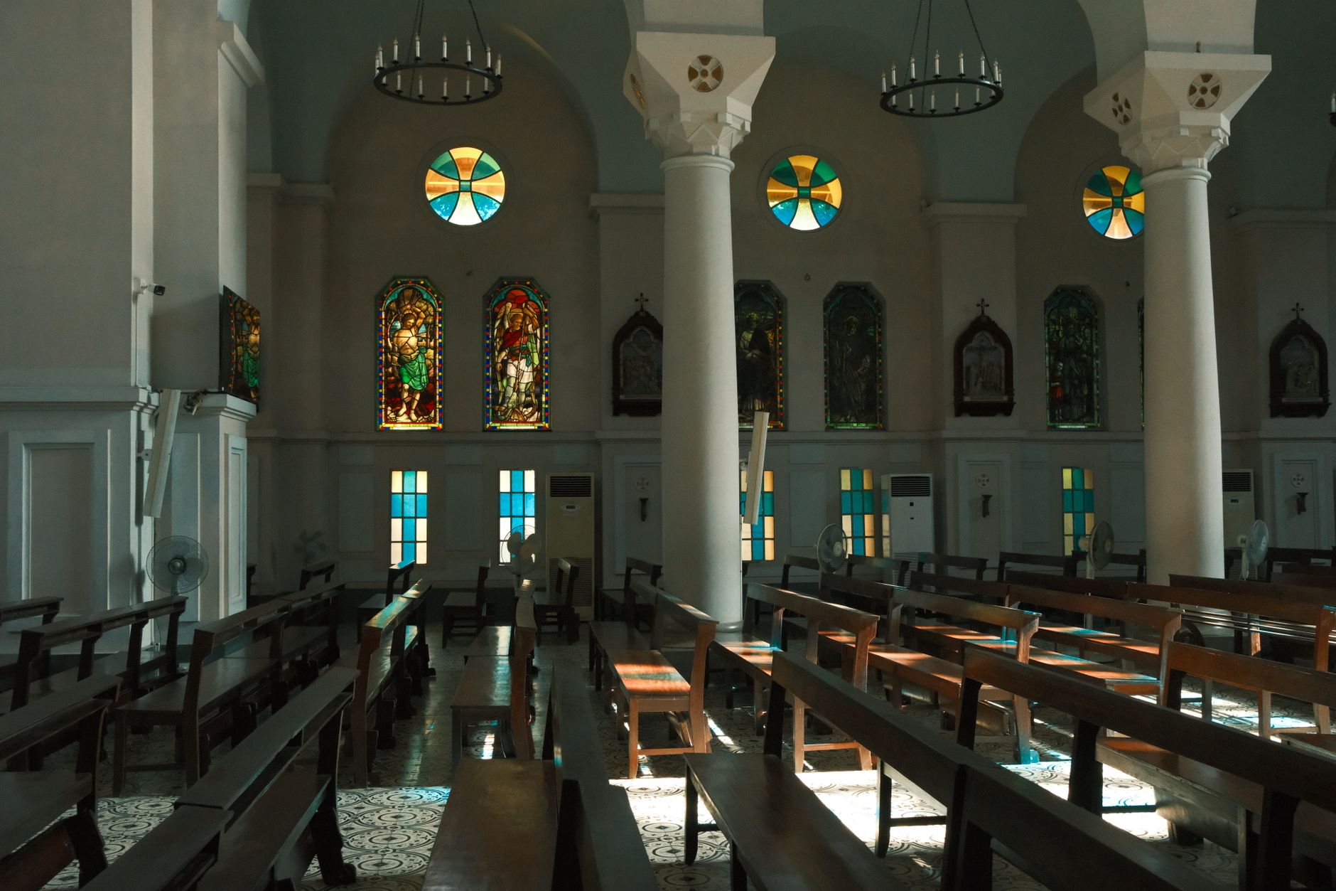 Sunlit church interior with stunning stained glass windows and wooden pews.
