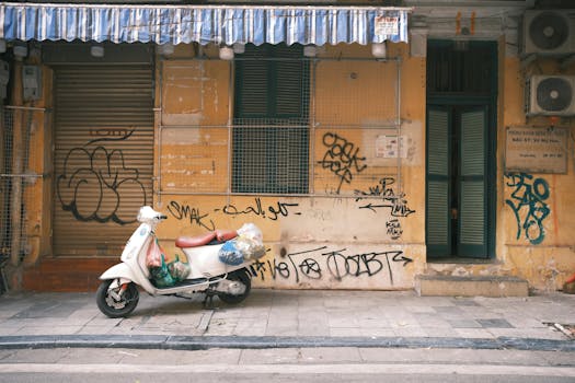 A classic scooter parked by a graffiti-covered wall in Hanoi, Vietnam, showcasing urban street art and culture.