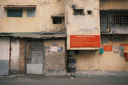 Free Aged building facade in Hanoi captured on a quiet street with signs in Vietnamese. Stock Photo