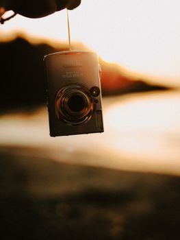 Close-up of a vintage camera held against a sunset backdrop.