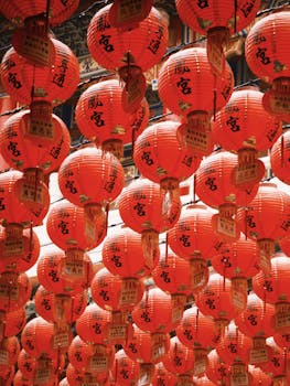 Colorful red lanterns with Chinese characters create a lively atmosphere in a traditional cultural setting.