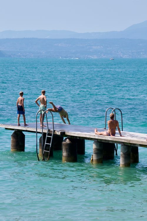 Free Group of teenagers enjoying summer on a wooden pier by the lake. Stock Photo