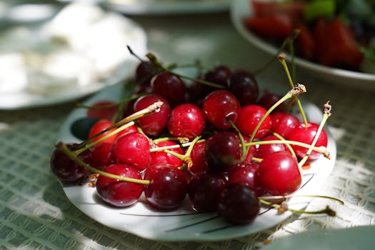 A close-up shot of fresh red cherries arranged on a decorative plate under natural light.