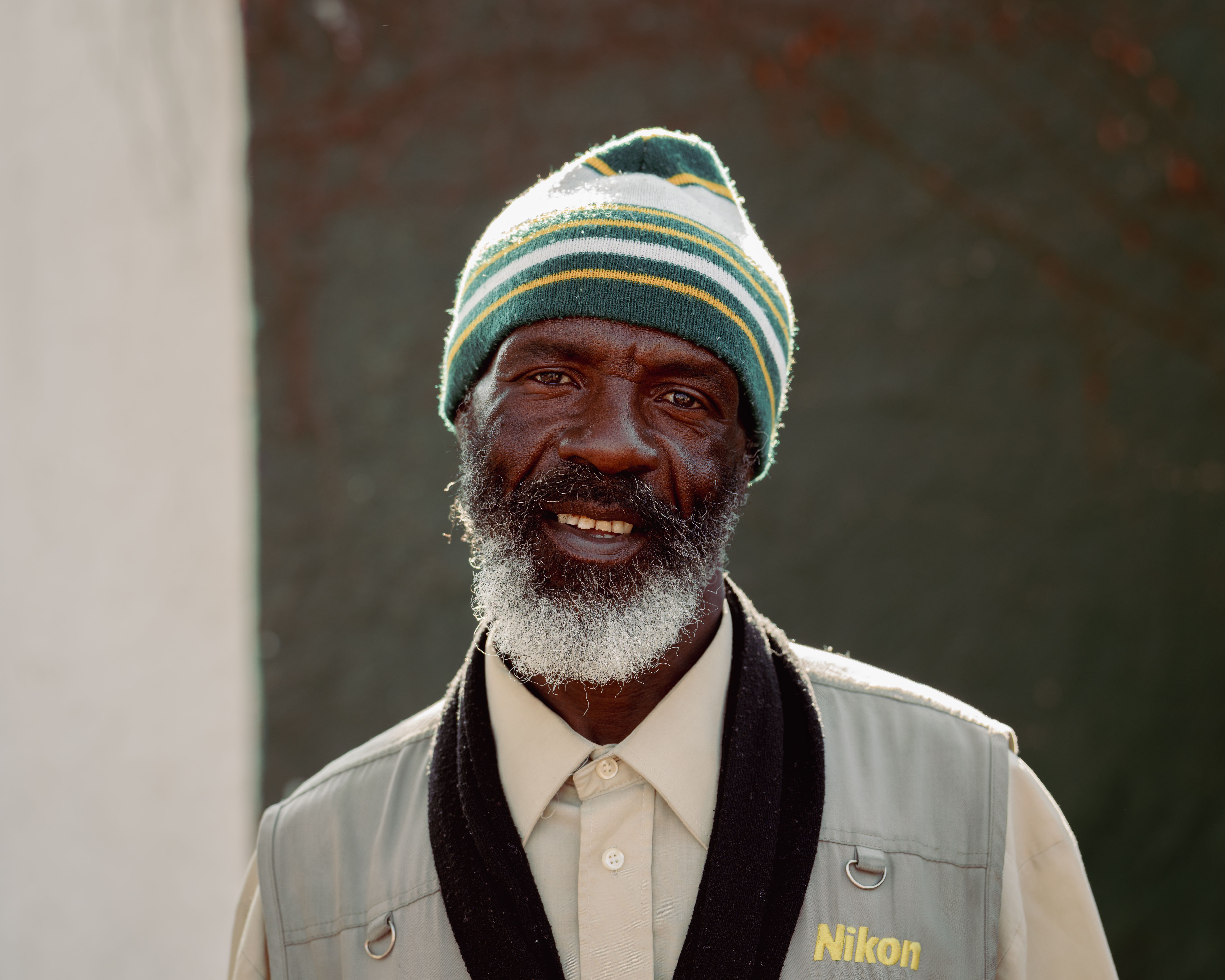A candid street portrait of a smiling man wearing a beanie in Johannesburg, South Africa.