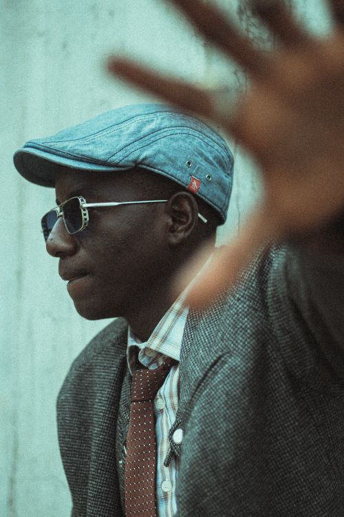 Free A man in a vintage suit and hat gestures to block the camera, creating a mysterious vibe. Stock Photo
