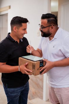 Two men happily exchanging a package indoors.
