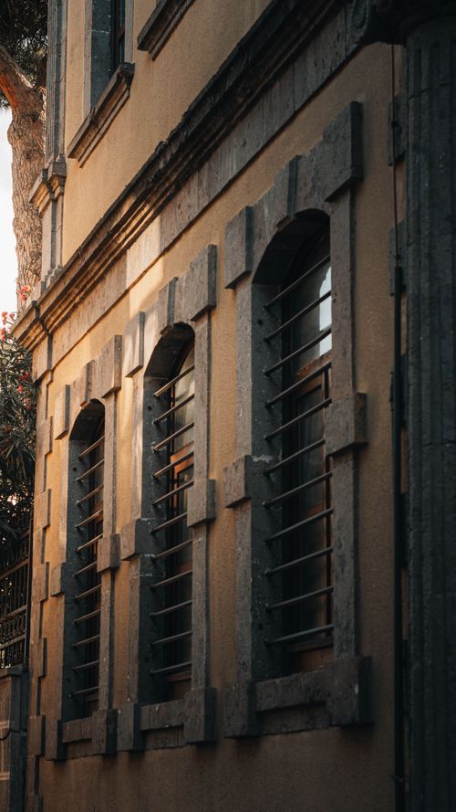 Free A vintage building facade featuring barred windows with warm lighting. Ideal for architectural themes. Stock Photo