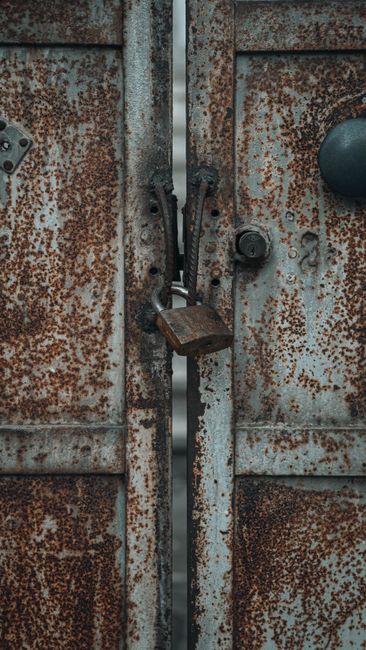 Fotomural Primer plano de una puerta de metal oxidada asegurada con un candado, transmitiendo fuerza y seguridad.