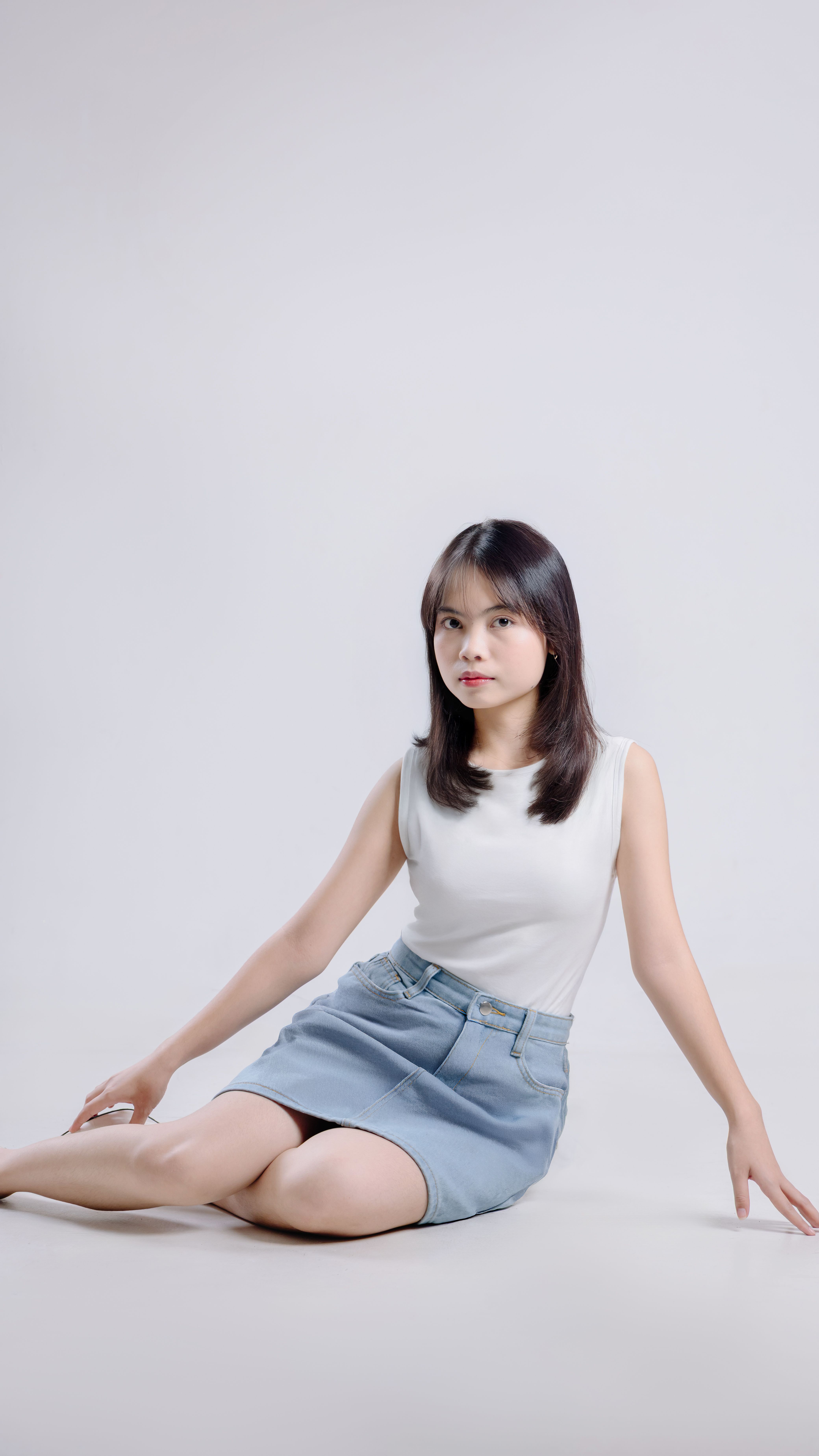 Woman wearing a white top with a medium-wash denim mini skirt