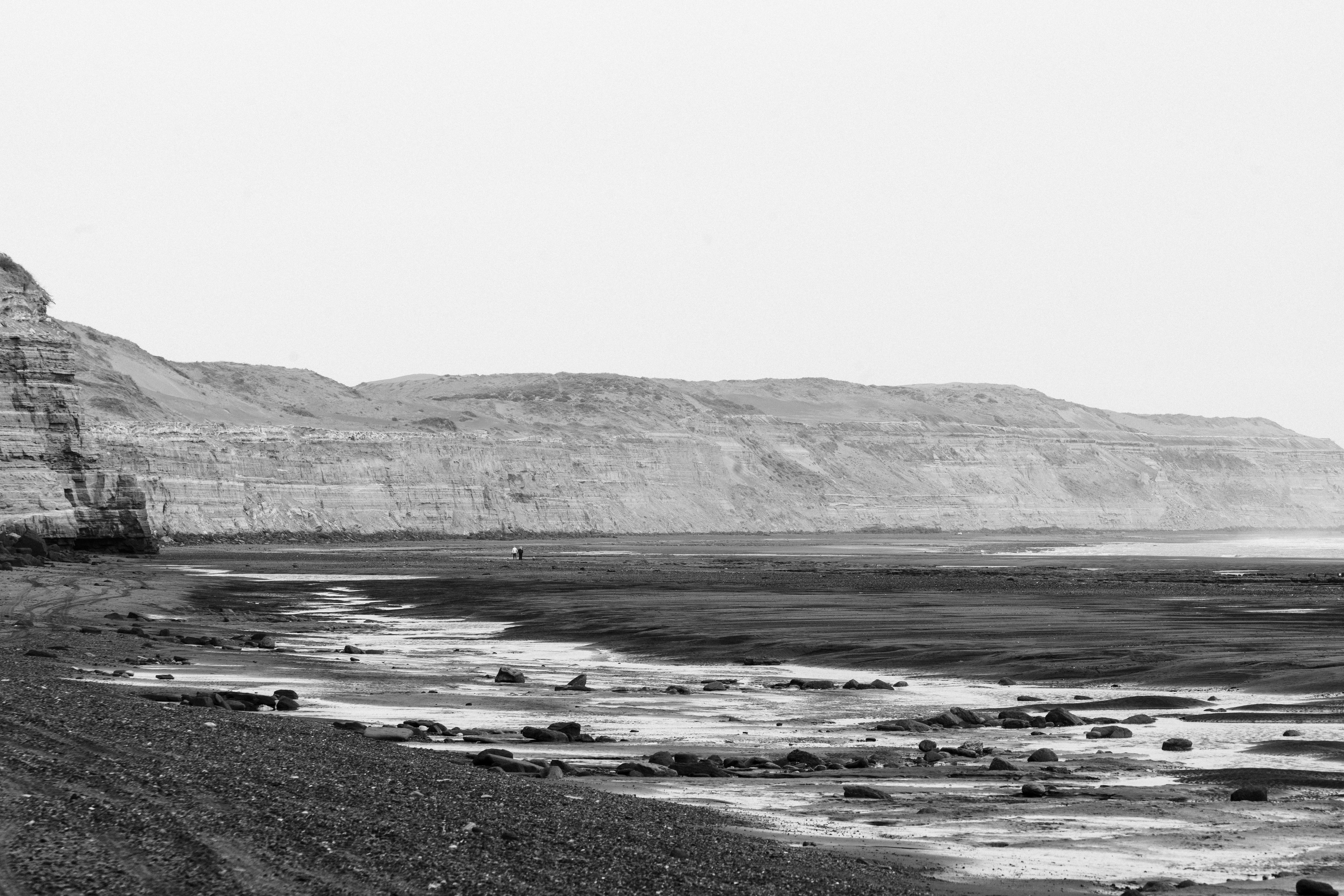 A tranquil black and white view of Bahía Creek's shoreline, capturing the rugged cliffs and serene beach.