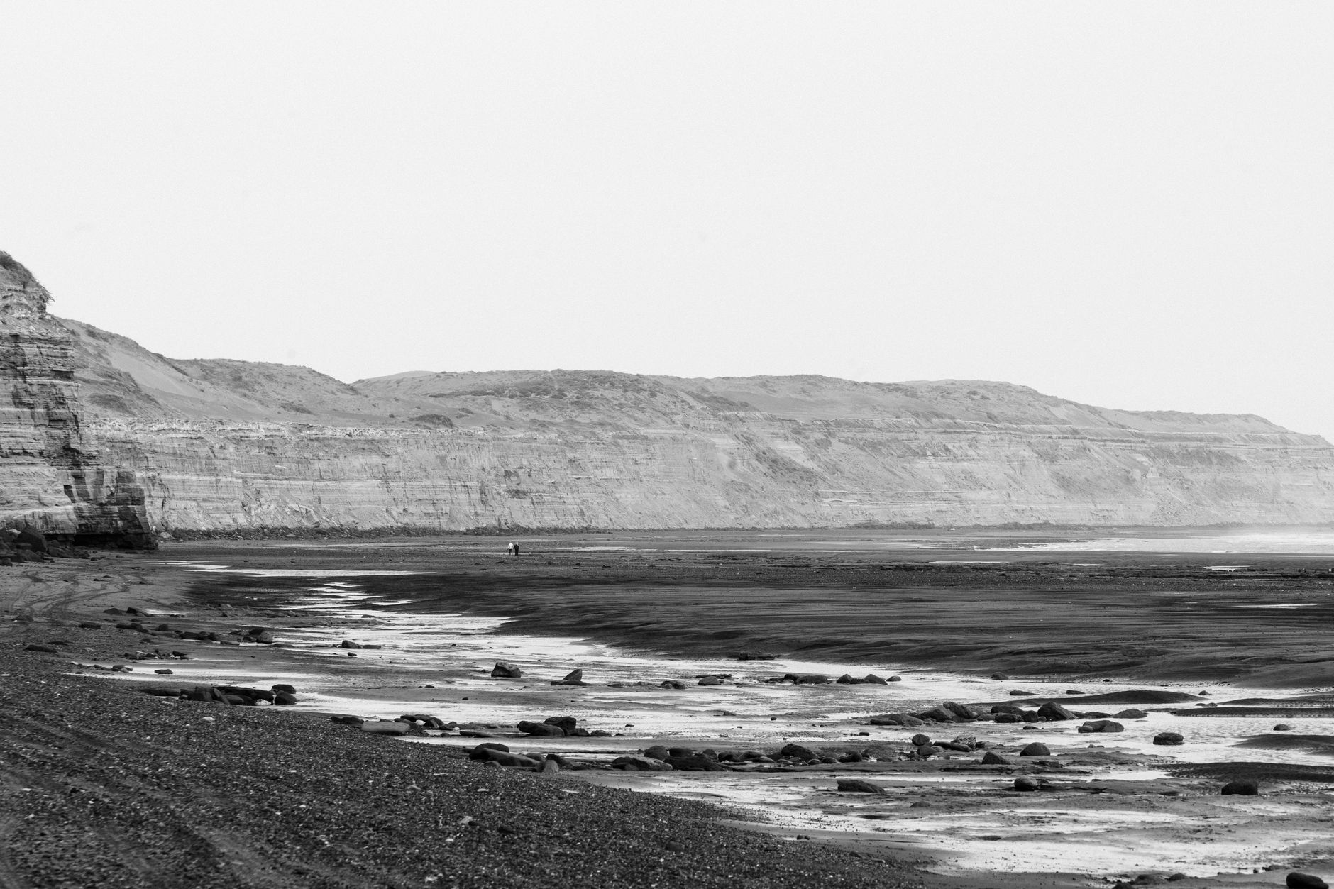 A tranquil black and white view of Bahía Creek's shoreline, capturing the rugged cliffs and serene beach.