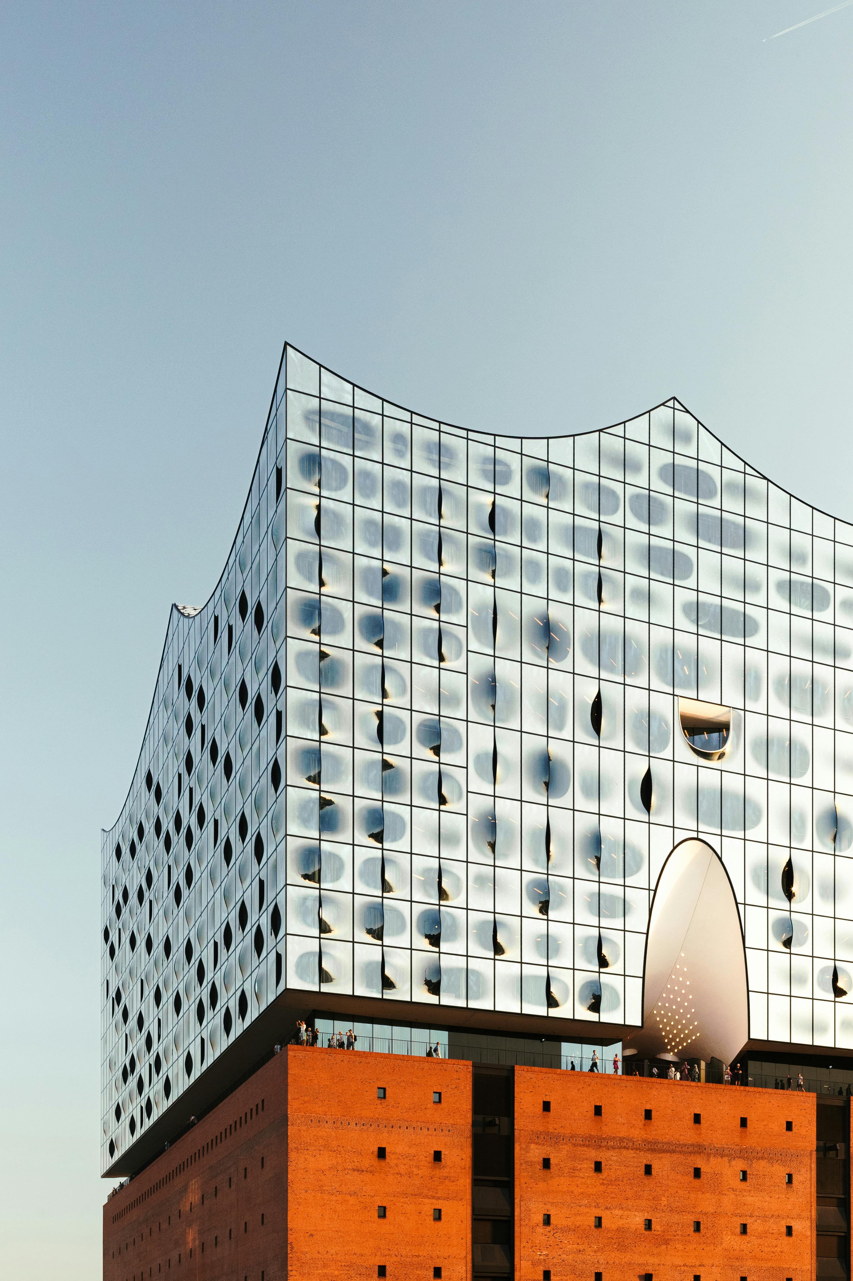 Modern architecture of Elbphilharmonie in Hamburg with a striking glass facade and brick base at sunset.