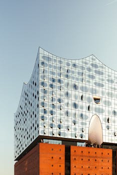 Modern architecture of Elbphilharmonie in Hamburg with a striking glass facade and brick base at sunset.