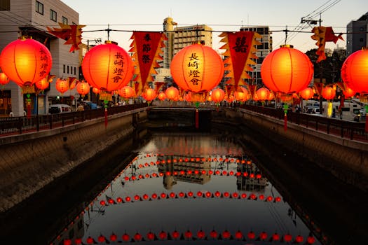 Brightly lit lanterns line a canal in Nagasaki, Japan, reflecting vibrantly in the calm water.