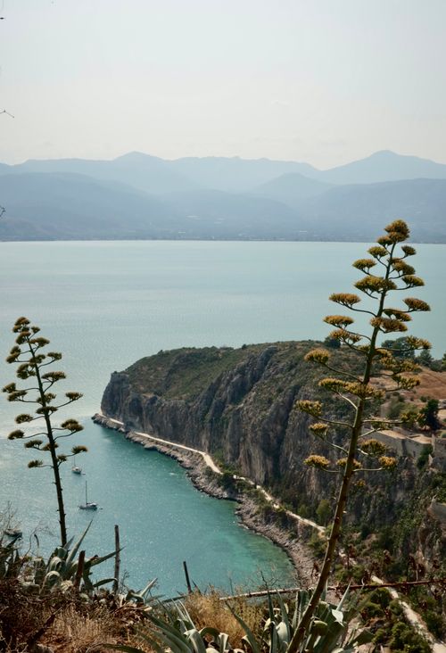 Free A breathtaking view of Nafplion's rocky coastline with sailboats and clear summer skies. Stock Photo