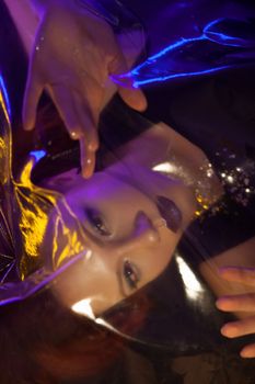 霓虹灯下，一位女性的戏剧性艺术肖像，展现出鲜艳的色彩与反光表面