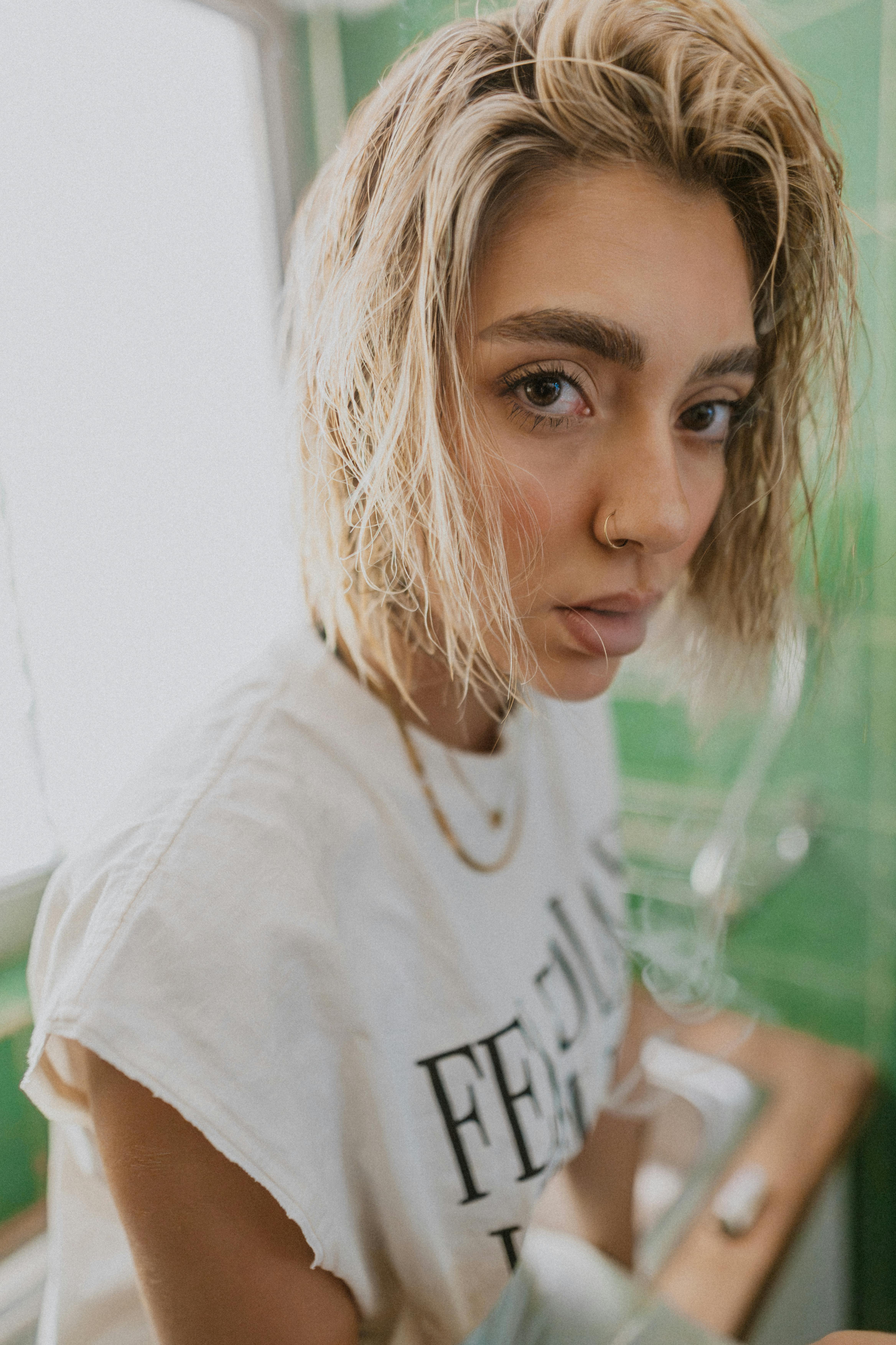 Kostnadsfria Porträtt av en ung kvinna med trendig stil i ett ljust, minimalistiskt badrum. Stock foto