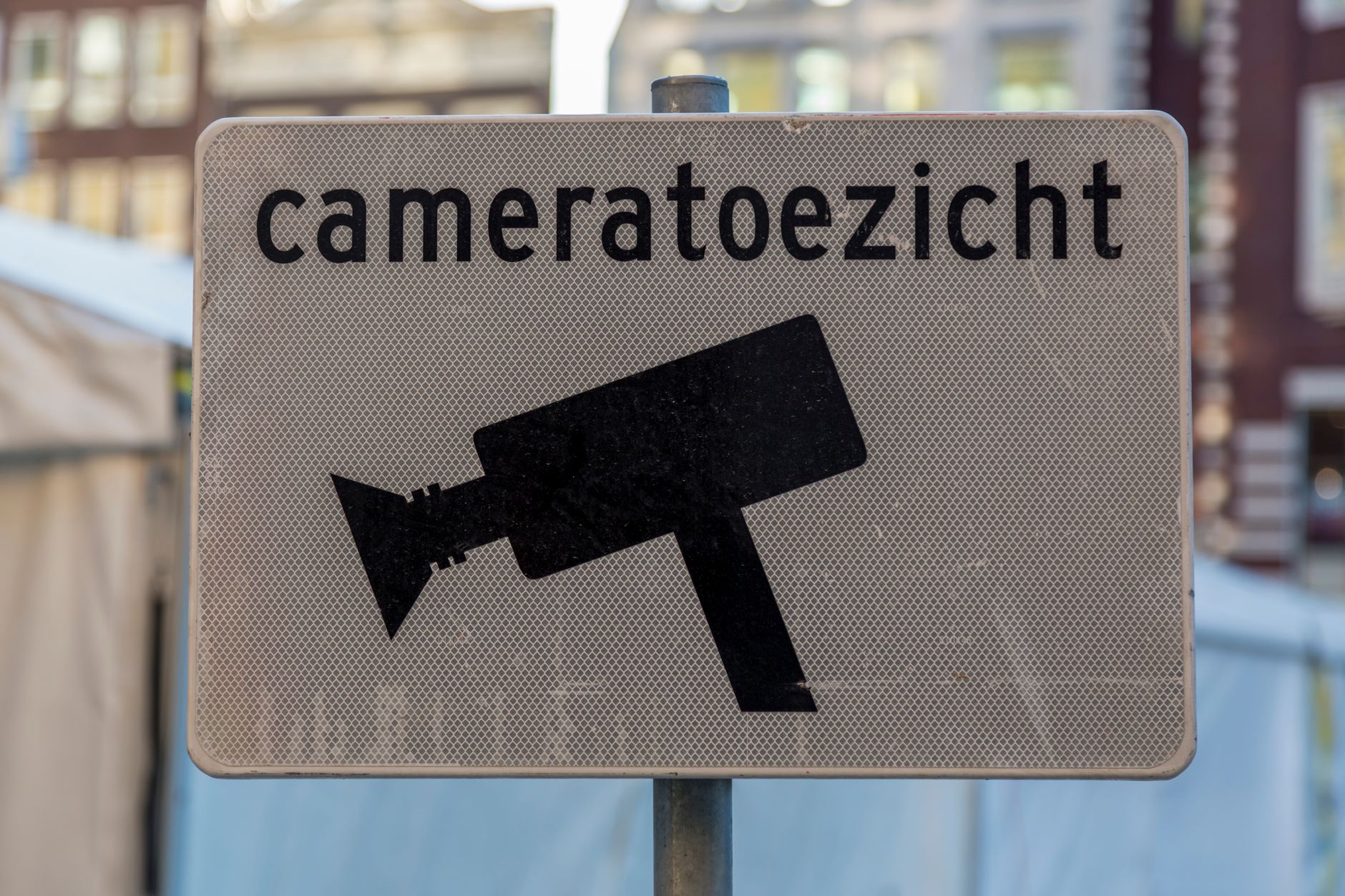 Close-up of a 'cameratoezicht' sign indicating surveillance in a city environment.