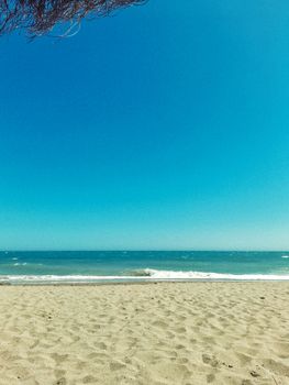 Serene beach setting with clear blue sky and gentle waves, perfect for relaxation and travel inspiration.