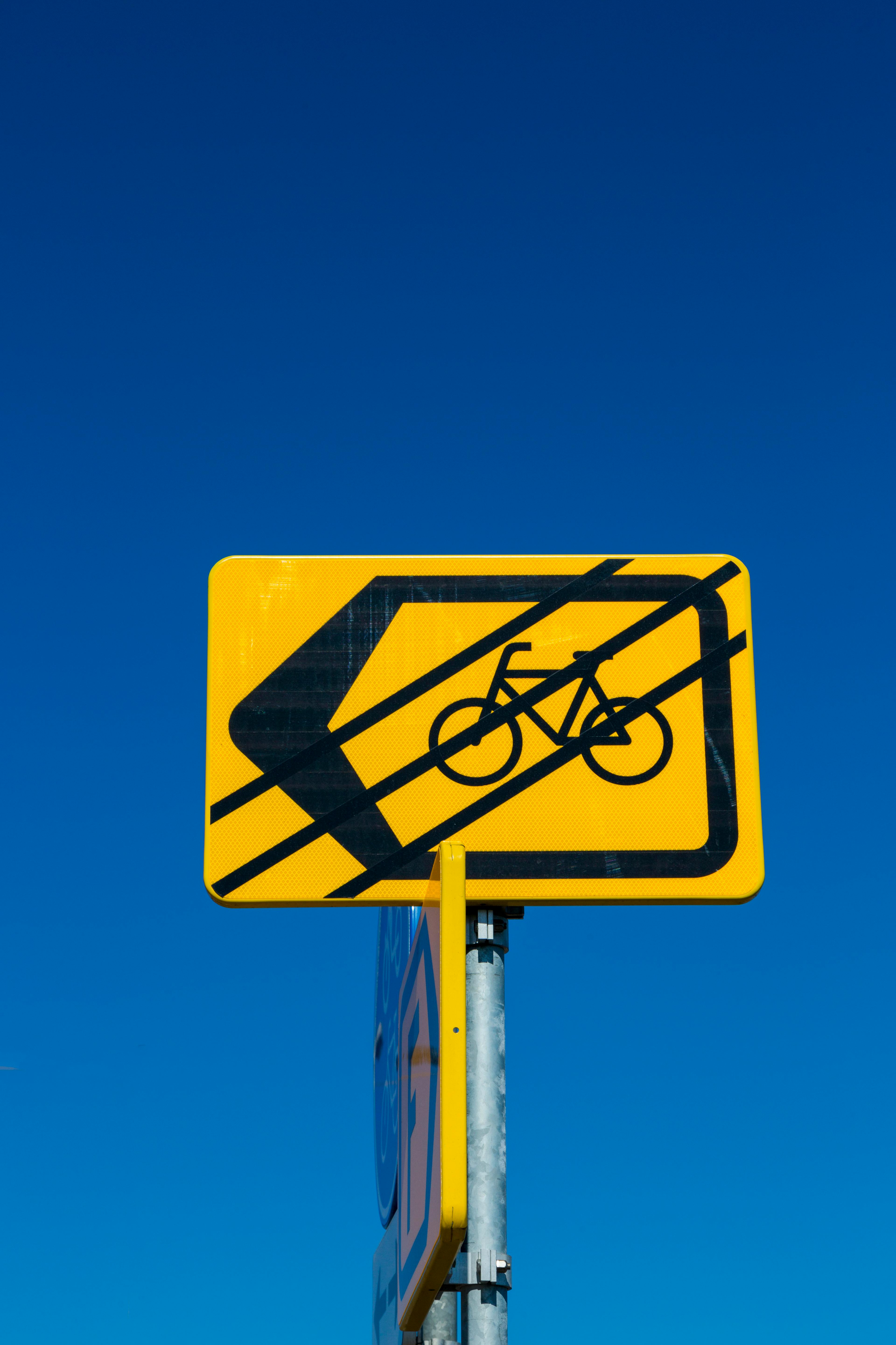 Gratis Gult trafikskilt for cykelsti med pil på en klar blå himmel baggrund, der fremhæver transportsikkerhed. Lagerfoto