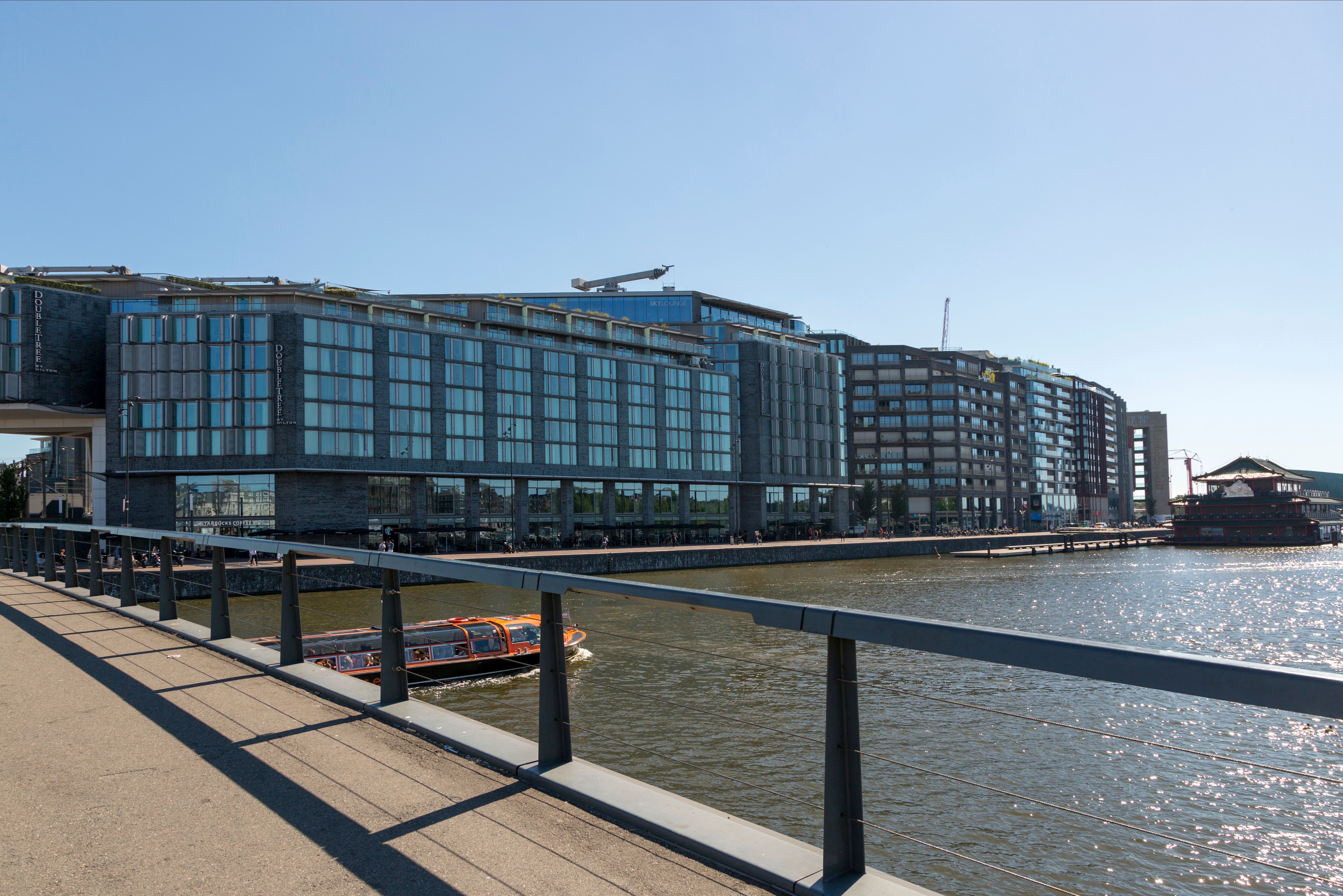 Contemporary waterfront buildings in Amsterdam under a clear blue sky.