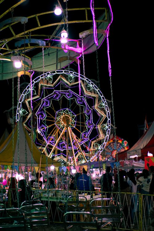 Free Colorful Ferris wheel lights up the night at Bali's lively carnival, creating a festive atmosphere. Stock Photo