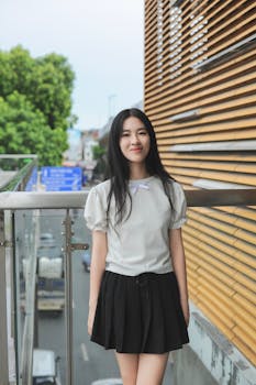 A young woman posing outdoors in Hanoi, showcasing modern street style with a natural backdrop.