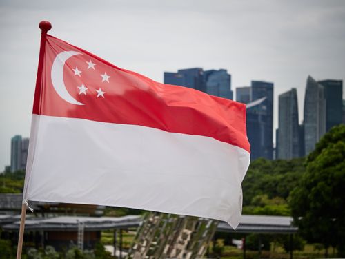 Free Singapore national flag waving with city skyline backdrop, symbolizing pride and modernity. Stock Photo