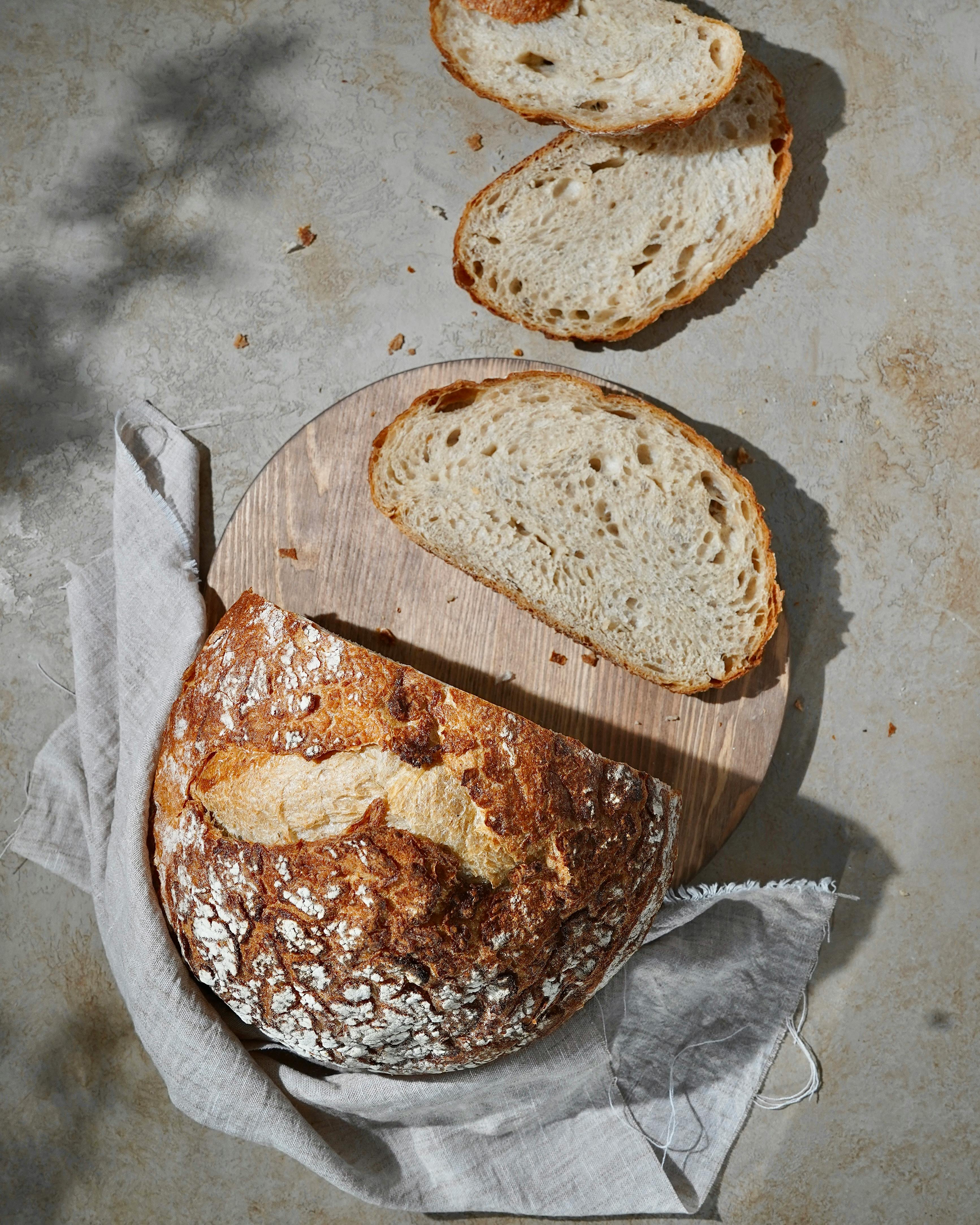 Artisan sourdough bread with slices on a wooden board, rustic kitchen style.