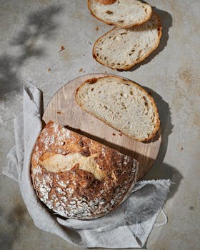 Artisan sourdough bread with slices on a wooden board, rustic kitchen style.
