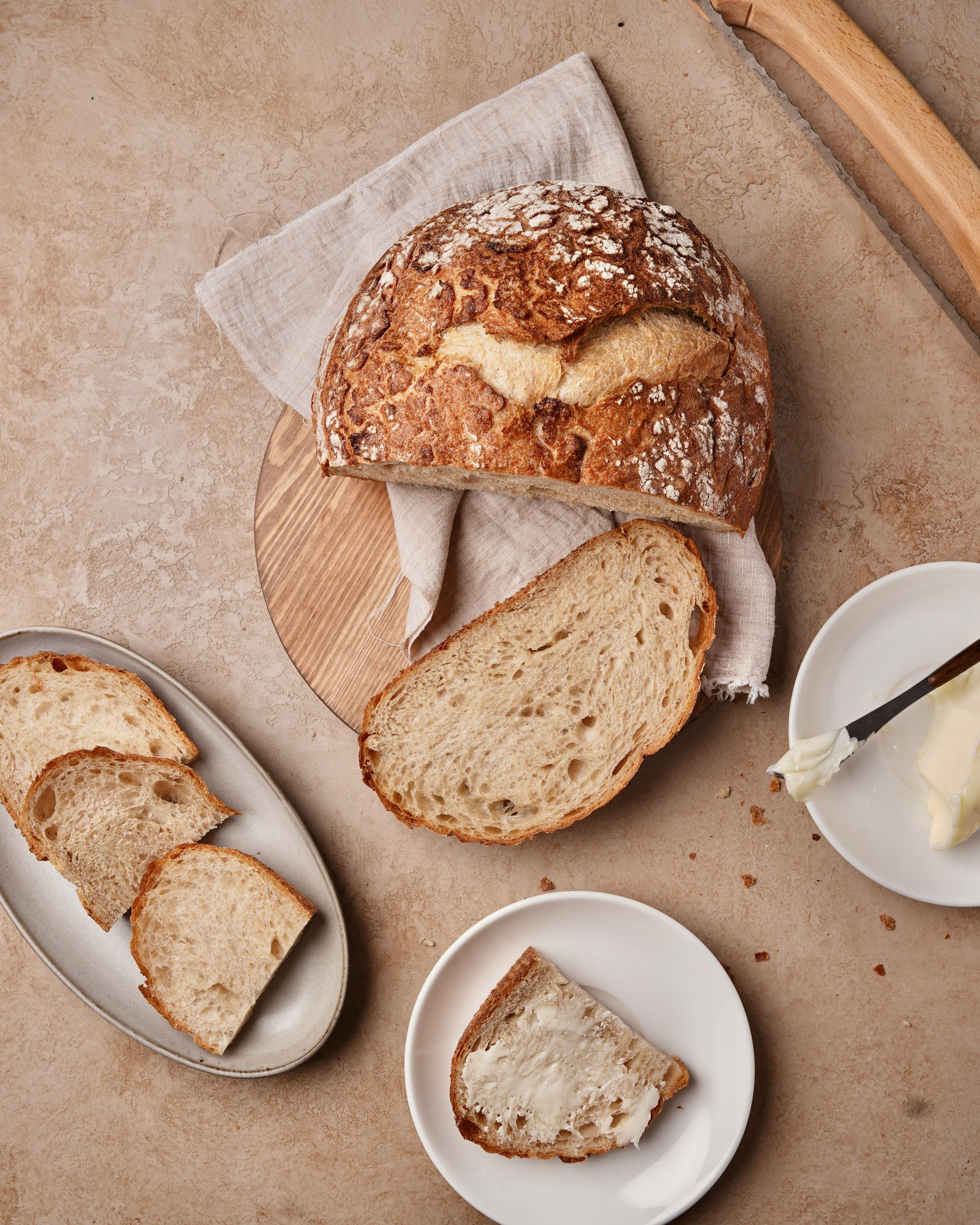 Delicious homemade sourdough bread with butter on a rustic table setting.