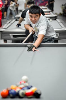 A concentrated player lines up a shot in an indoor billiards hall in Hà Nội, Việt Nam.