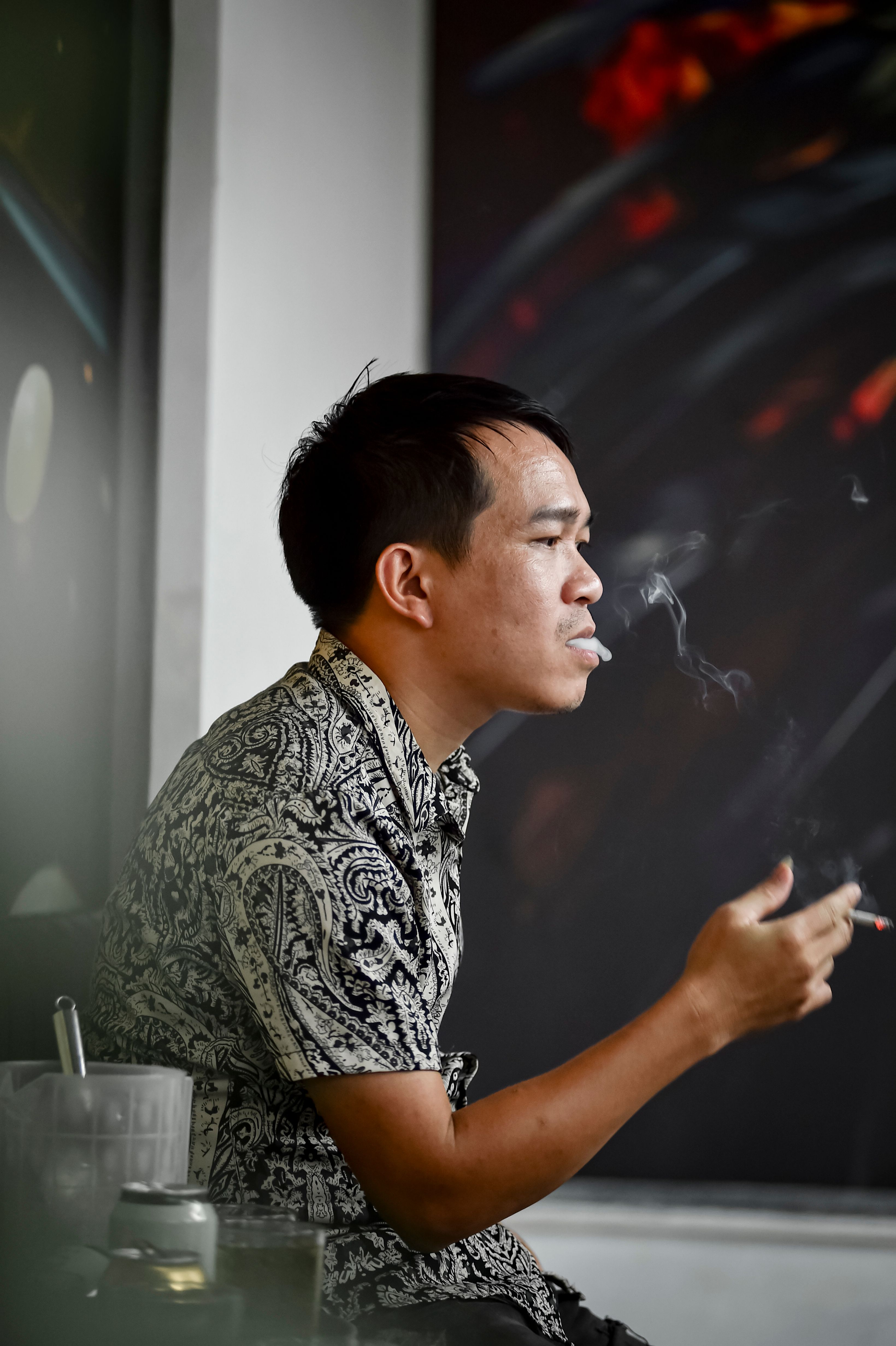 Profile of a man smoking indoors, captured in Hà Nội, Vietnam.