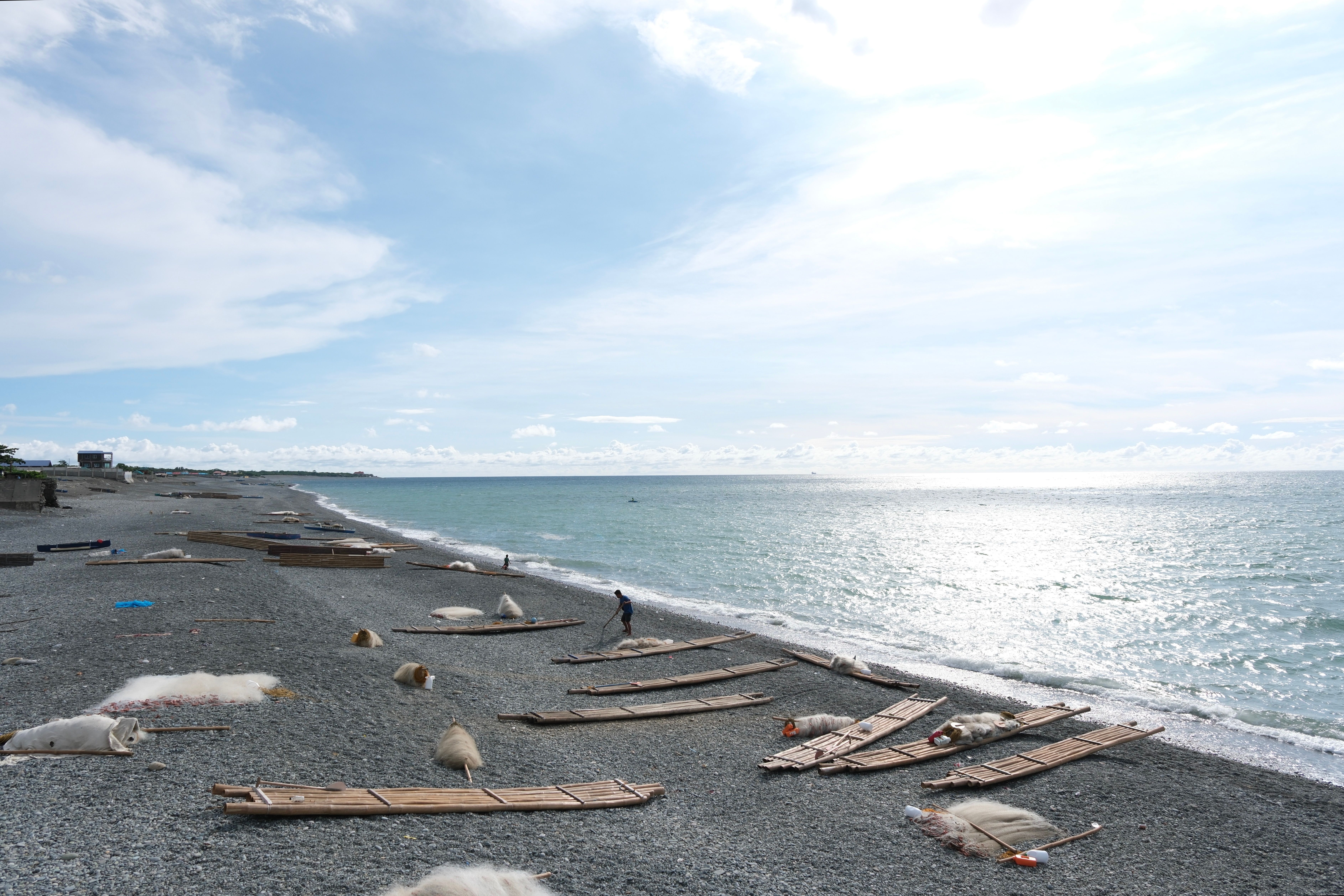 A sunny beach scene with bamboo racks drying fish nets in the Ilocos Region, Philippines.